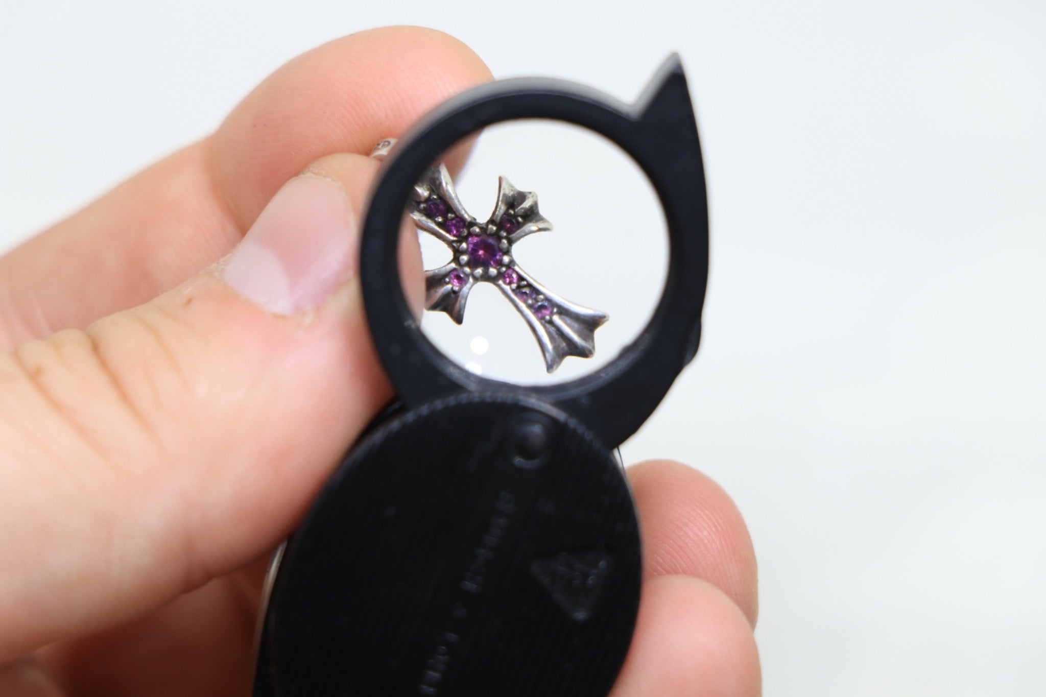 AVNTGRDNY authenticating Chrome Hearts jewelry under magnification